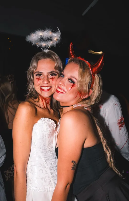 Zwei Freundinnen als Engel und Teufelin, Wange an Wange, bei Spooky Flame im Wartesaal am Dom, Köln