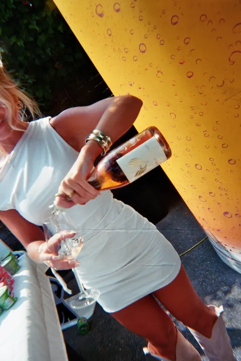 Eine Frau in Weiß schenkt sich ein Glas HEAVEN ein